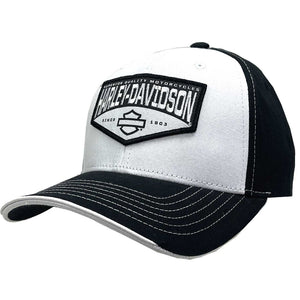 A black and white Harley-Davidson trucker-style baseball cap with a white front panel, black side and back panels, a black brim, and a black embroidered patch on the front featuring the brand name and logo.