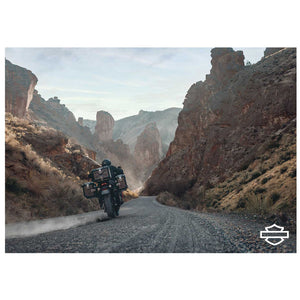 Motorcycle on a desert road with rocky cliffs and a clear sky