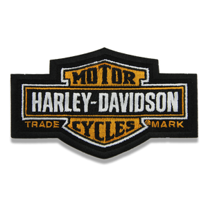 Harley-Davidson embroidered patch in the brand's signature shield shape, featuring black, white, and gold colors with the text 'MOTOR HARLEY-DAVIDSON' and 'TRADE CYCLES MARK'.