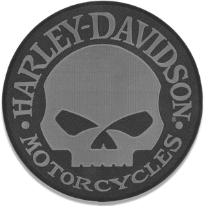 A circular Harley-Davidson Motorcycles embroidered patch featuring a gray skull emblem in the center with the brand name arched above and below in gray lettering on a black background.