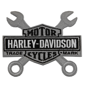 A Harley-Davidson Motor Trade Cycles patch featuring a black and silver design with crossed wrenches and the brand name.