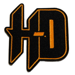 A stylized embroidered patch featuring the letters 'HD' in black with a bright orange-yellow border and fill, shown on a plain white background.