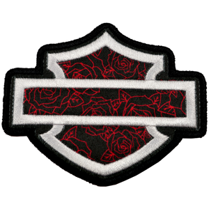 An embroidered shield-shaped patch featuring a black and red rose pattern with a white horizontal bar across the center, outlined in black and white.