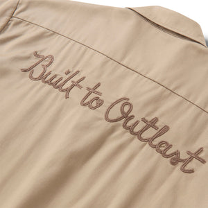 Beige jacket with 'Built to Outlast' embroidery on a beige background