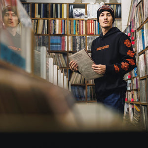 Person wearing a black hoodie with orange text in a library setting