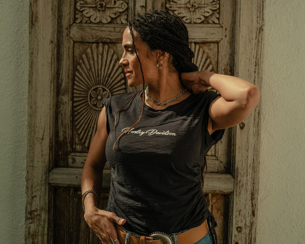 Person wearing a Harley Davidson t-shirt in front of a decorative wooden door.