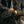 Person wearing black gloves with a logo, holding hands together, against a blurred background.
