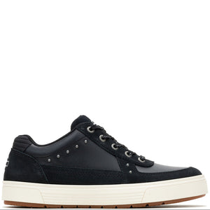 A low-top sneaker in black suede and leather with silver metal studs, black laces, and a thick off-white midsole, shown from a side profile on a white background.