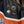 Four Harley-Davidson themed enamel pins displayed on a black leather motorcycle jacket with orange and white racing stripes.