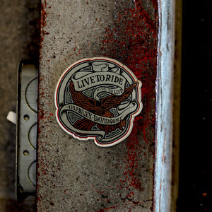 A die-cut vinyl sticker featuring a Harley-Davidson eagle and crossed axes design with the text 'LIVE TORIDE' and 'Harley-Davidson', shown applied to a weathered metal surface.