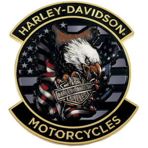 A circular Harley-Davidson Motorcycles enamel pin featuring a bald eagle holding a Harley-Davidson bar and shield, set against a black American flag background with gold lettering.