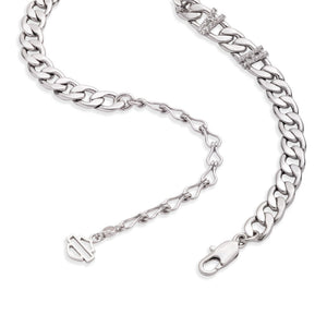 A silver-toned Cuban link chain bracelet with a lobster clasp, extension chain, and a small interlocking 'I' charm, shown on a plain white background.
