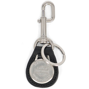 A Harley-Davidson keychain featuring a black leather teardrop-shaped pouch with a silver-tone metal clasp, key ring, and a round silver-tone Harley-Davidson emblem on a white background.
