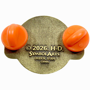 A vintage-style enamel pin or badge featuring two bright orange bulb-like shapes on either side of a textured gold oval backing, with embossed text reading '© 2026. H-D.