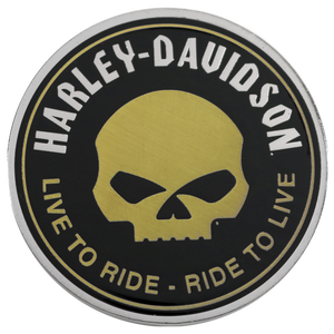 A circular Harley-Davidson emblem or badge with a black face, a large gold skull in the center, and white and gold text reading 'HARLEY-DAVIDSON' and 'LIVE TO RIDE - RIDE TO LIVE' around the border.