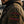 Close-up of a man wearing a dark brown denim jacket with a large embroidered Harley-Davidson patch on the sleeve, set against an outdoor urban background.