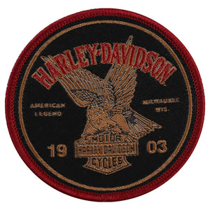 A circular embroidered Harley-Davidson patch featuring a black background, red border, tan eagle, and red and tan text including 'HARLEY-DAVIDSON', 'AMERICAN LEGEND', 'MULTIAGE 915', and '19 03'.