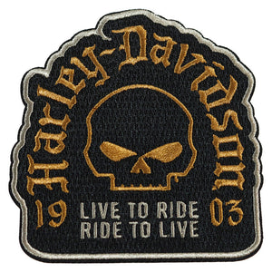 An embroidered Harley-Davidson patch featuring a black background with a gold skull in the center, the words 'Harley-Davidson' in gold around the top, and 'LIVE TO RIDE RIDE TO LIVE' with numbers '19' and '03' in white and gold at the bottom.
