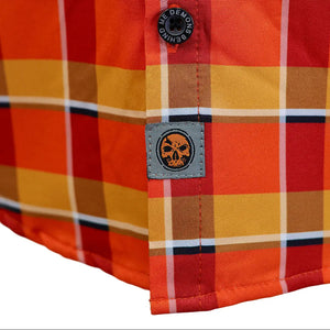 Close-up of a plaid button-up shirt corner showing orange, yellow, and red stripes with a black button and a gray brand patch.