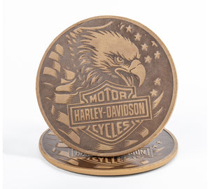 Two round wooden coasters featuring a detailed Harley-Davidson motorcycle logo and eagle design, stacked on a white background.