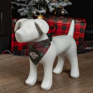 White ceramic dog figurine wearing a plaid bandana in front of a Christmas tree and presents.