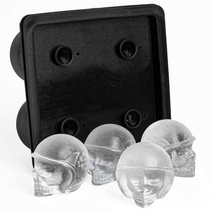 A black silicone mold tray with four circular cavities, shown with four clear skull-shaped ice cubes in front on a white background.