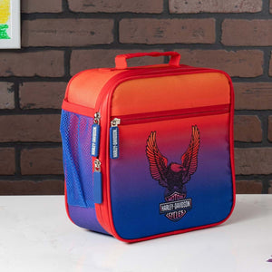 Red and blue insulated lunch bag with Harley-Davidson logo against a brick wall.
