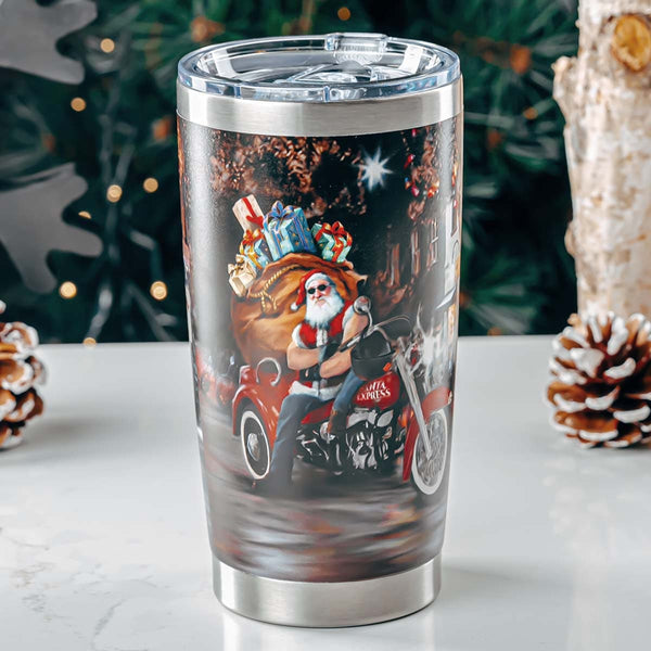 Clear tumbler with a design of Santa Claus on a motorcycle, surrounded by gifts, against a Christmas-themed background.