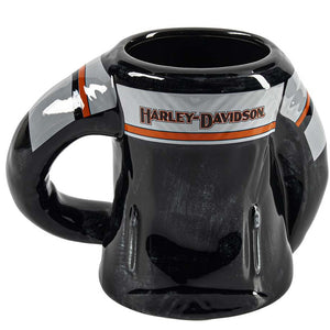 A glossy black ceramic mug designed in the shape of a Harley-Davidson motorcycle tank, featuring the brand's logo on a white stripe with orange accents.