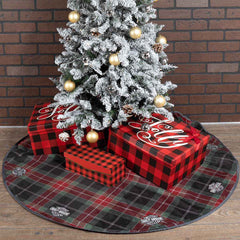 Decorative Christmas tree with red and black plaid presents and a matching tree skirt against a brick wall.