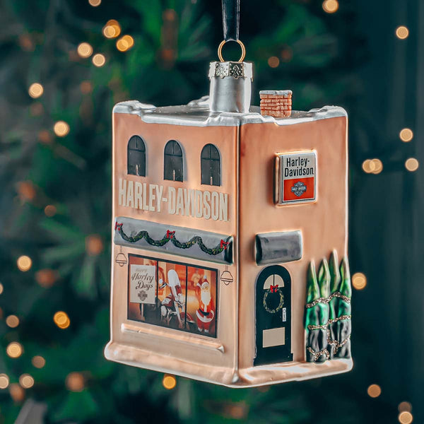 Harley-Davidson-themed building ornament on a Christmas tree with blurred lights in the background.