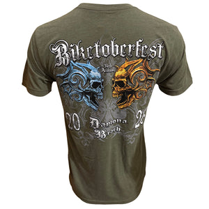 An olive green short-sleeve t-shirt shown from the back, featuring a large graphic print with two stylized skulls in blue and orange, the text 'Biktoberfest', '2026', and 'Bayona Beach'.