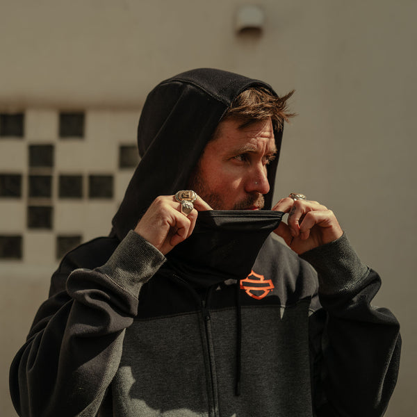 Man wearing a black hoodie with a visible brand logo, holding a wallet.