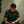 Man wearing a Harley Davidson cap and shirt, sitting against a white wall.