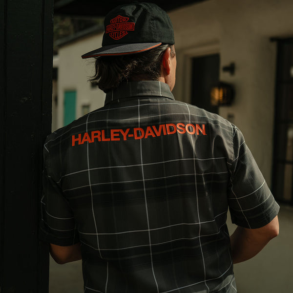 Person wearing a Harley-Davidson shirt and cap in an indoor setting