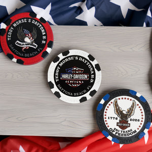 Three Harley-Davidson branded poker chips on a wooden surface with an American flag in the background.