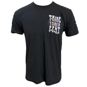 A black short-sleeve t-shirt with a distressed graphic on the left chest reading 'TRIKE TOBER ZEST' in white, red, and blue, displayed on a solid white background.